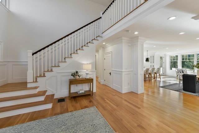 stairway with wood-type flooring and crown molding