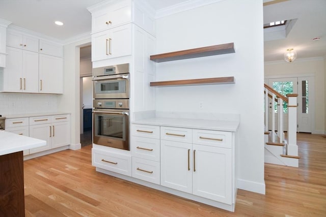 kitchen featuring tasteful backsplash, white cabinetry, crown molding, and stainless steel double oven