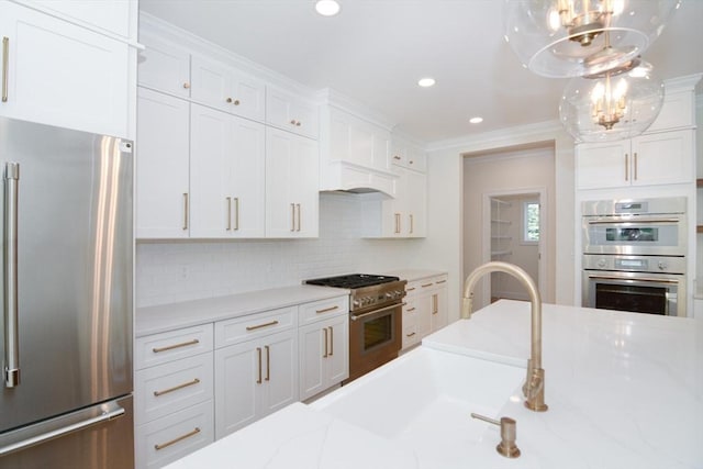 kitchen featuring light stone countertops, tasteful backsplash, stainless steel appliances, decorative light fixtures, and white cabinetry