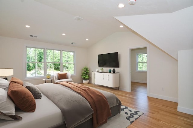 bedroom with vaulted ceiling, light hardwood / wood-style flooring, and multiple windows