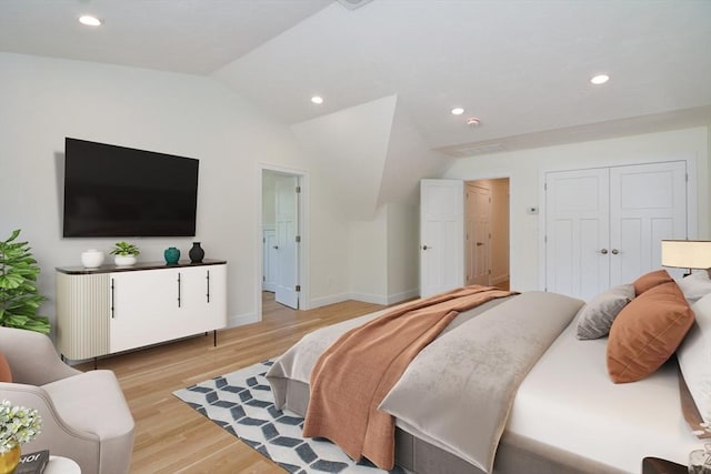 bedroom with a closet, lofted ceiling, and light wood-type flooring