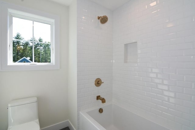 bathroom featuring toilet and tiled shower / bath