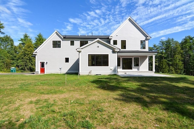 back of property with a lawn, a patio area, and solar panels