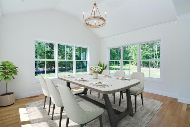 dining area featuring a chandelier, lofted ceiling, and light wood-type flooring