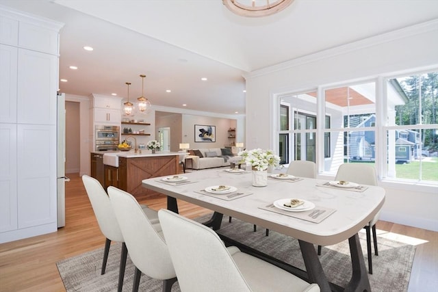 dining room with a wealth of natural light, crown molding, and light hardwood / wood-style floors