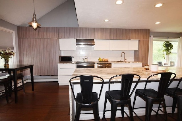 1559 Bay St Unit 53, Taunton, MA 02780 - kitchen with stainless steel appliances, wall chimney exhaust hood, a kitchen bar, white cabinets, and pendant lighting