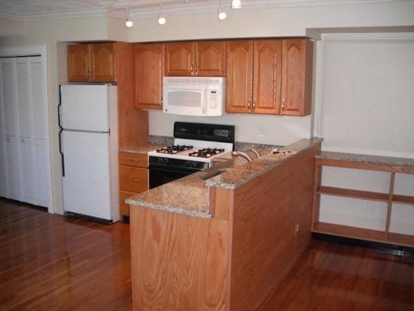 kitchen featuring white appliances, ornamental molding, kitchen peninsula, light stone countertops, and dark hardwood / wood-style floors