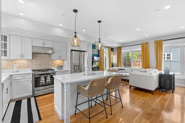 kitchen with appliances with stainless steel finishes, decorative light fixtures, a kitchen island, and white cabinets