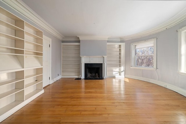 unfurnished living room with baseboards, light wood-type flooring, a fireplace with flush hearth, and crown molding