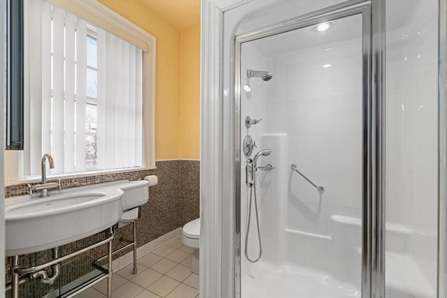 full bathroom featuring toilet, wainscoting, tile patterned floors, a stall shower, and plenty of natural light