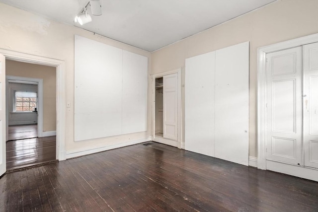 unfurnished bedroom with dark wood-style floors and two closets