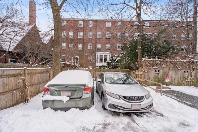 snow covered parking area with fence