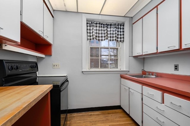 kitchen with electric range, white cabinets, light wood-style flooring, open shelves, and a sink