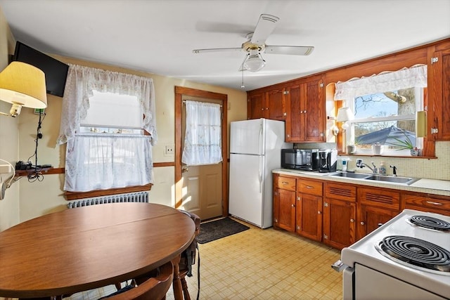 kitchen with backsplash, radiator, white appliances, ceiling fan, and sink