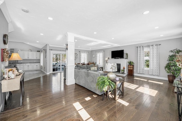 living area with recessed lighting, dark wood-style flooring, a fireplace, baseboards, and decorative columns