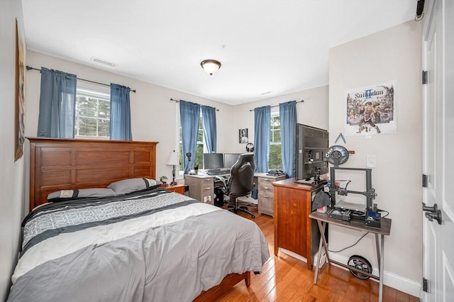 bedroom featuring multiple windows, light wood-type flooring, visible vents, and baseboards