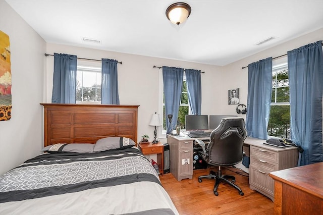 bedroom featuring light wood-style flooring, multiple windows, and visible vents