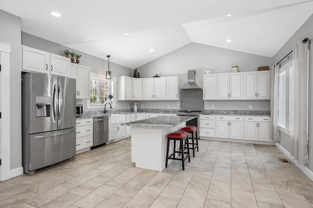 kitchen featuring stainless steel appliances, a breakfast bar, wall chimney range hood, a center island, and pendant lighting