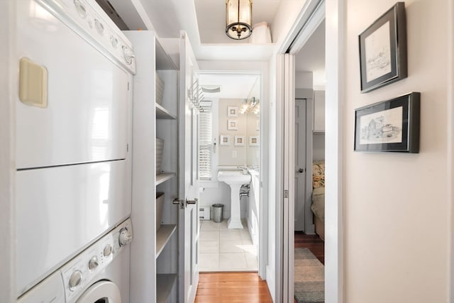 laundry area featuring stacked washer and dryer, light hardwood / wood-style floors, and sink