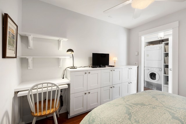 bedroom with stacked washer / drying machine, dark hardwood / wood-style flooring, built in desk, and ceiling fan