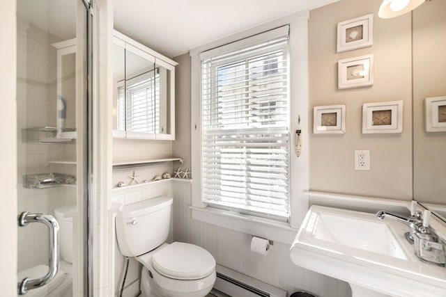 bathroom with a wealth of natural light, baseboard heating, sink, and toilet