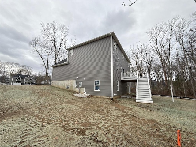 view of property exterior with stairway and a wooden deck