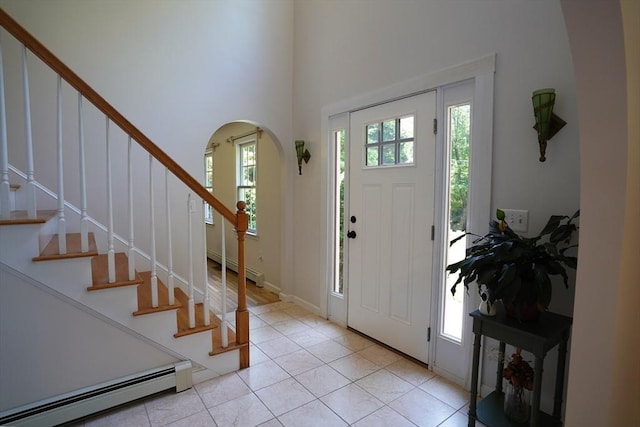 42 Wall St, Middleboro, MA 02346 - foyer entrance with a baseboard heating unit, arched walkways, stairs, light tile patterned flooring, and a towering ceiling
