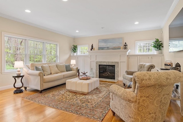 living room with wood finished floors, ornamental molding, baseboards, a high end fireplace, and recessed lighting