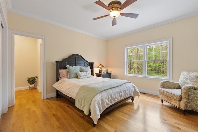 bedroom with light wood-style flooring, ornamental molding, baseboards, and a ceiling fan