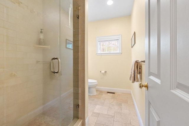 bathroom featuring a stall shower, toilet, and baseboards