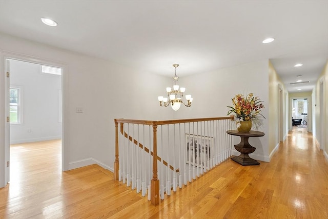 hallway with an upstairs landing, light wood-type flooring, a chandelier, recessed lighting, and baseboards