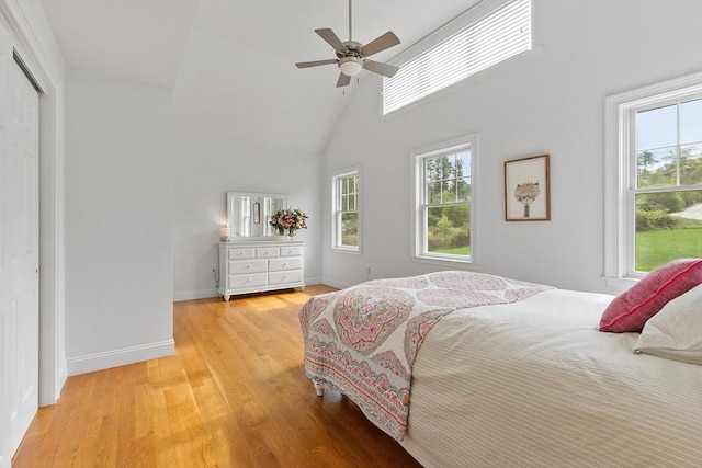 bedroom featuring multiple windows, high vaulted ceiling, light wood-style flooring, and baseboards