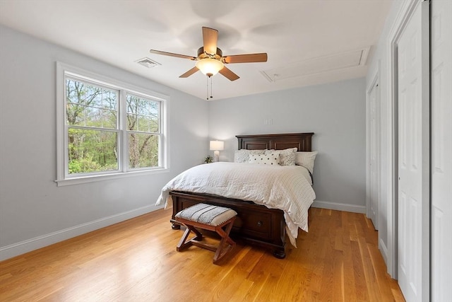 bedroom with baseboards, light wood-style flooring, attic access, and ceiling fan