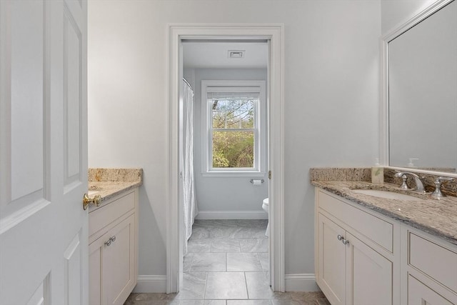 bathroom featuring vanity, baseboards, toilet, and marble look tile flooring