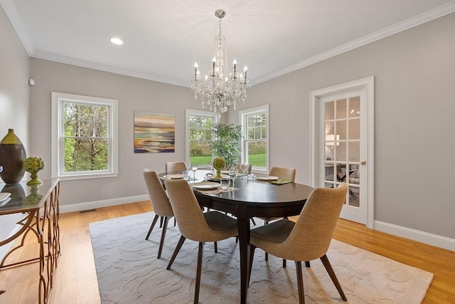 dining space with a chandelier, crown molding, plenty of natural light, baseboards, and light wood-style flooring