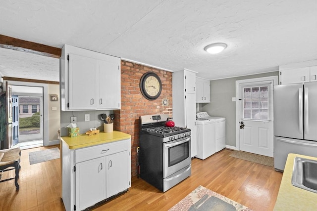 23 Garden Rd, Scituate, MA 02066 - kitchen with appliances with stainless steel finishes, washing machine and clothes dryer, light wood-type flooring, white cabinets, and a textured ceiling