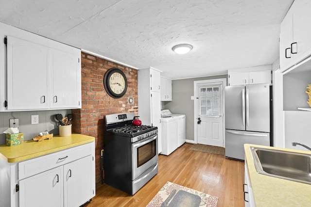 23 Garden Rd, Scituate, MA 02066 - kitchen with washing machine and dryer, appliances with stainless steel finishes, light countertops, light wood-style flooring, and a textured ceiling
