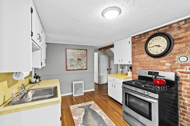 23 Garden Rd, Scituate, MA 02066 - kitchen featuring stainless steel range with gas stovetop, light countertops, light wood-style flooring, white cabinets, and a textured ceiling