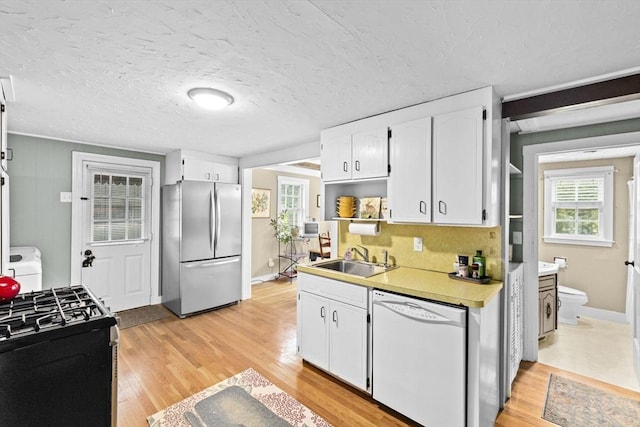 23 Garden Rd, Scituate, MA 02066 - kitchen with white dishwasher, freestanding refrigerator, range with gas cooktop, white cabinetry, and light wood-type flooring