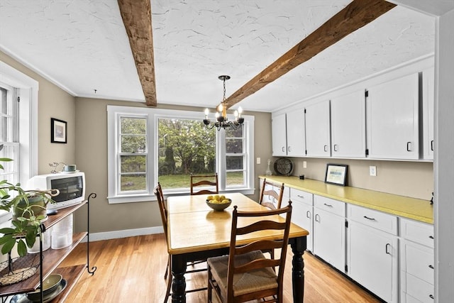 23 Garden Rd, Scituate, MA 02066 - dining area with beam ceiling, a chandelier, and light wood-type flooring