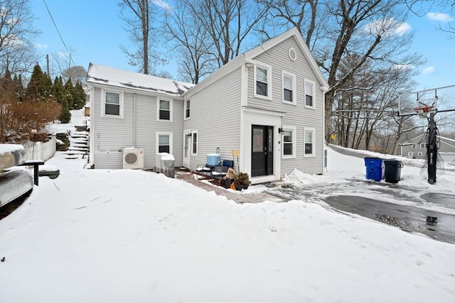 snow covered house featuring ac unit