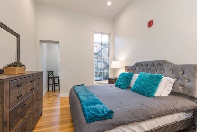 bedroom featuring recessed lighting, baseboards, light wood-style floors, and a towering ceiling