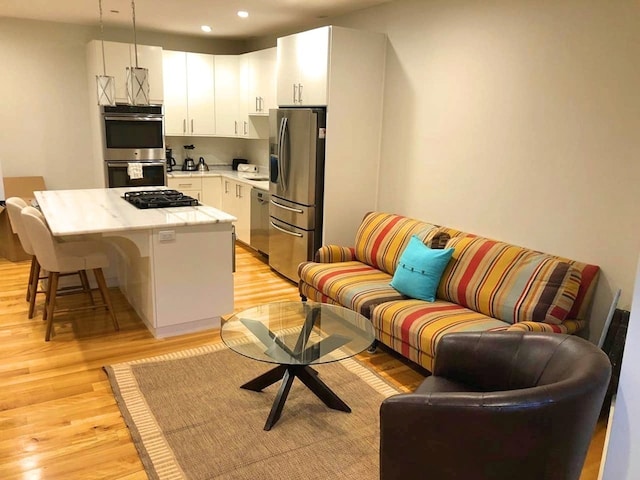 kitchen with a kitchen bar, light countertops, light wood-style floors, white cabinets, and stainless steel appliances