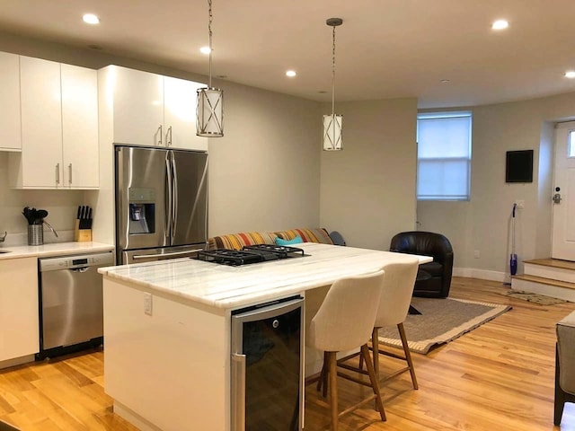 kitchen with wine cooler, light wood finished floors, a breakfast bar area, and appliances with stainless steel finishes