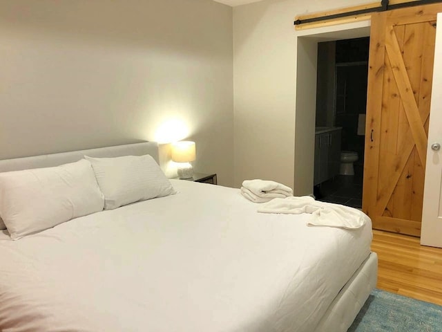 bedroom with a barn door and wood finished floors