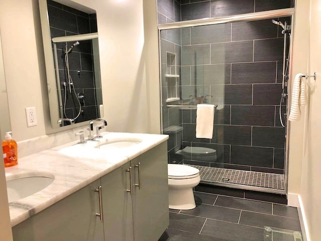 full bath featuring a sink, toilet, a stall shower, and double vanity