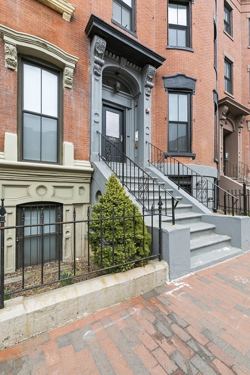 doorway to property with brick siding and fence