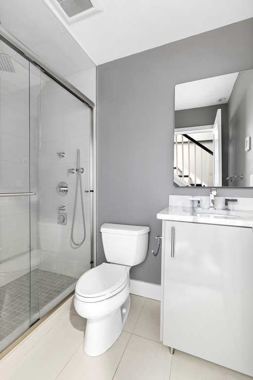 bathroom with vanity, a shower stall, toilet, and visible vents