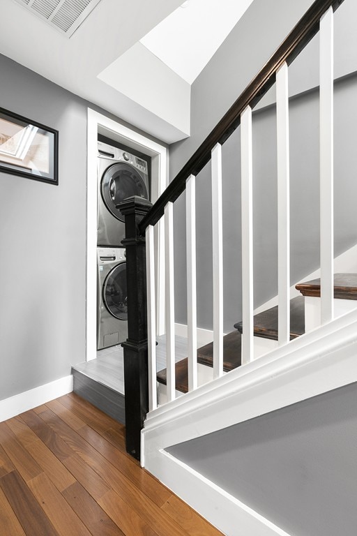 stairs with visible vents, baseboards, stacked washer and clothes dryer, and wood finished floors