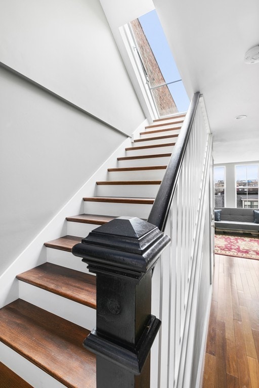 stairway with wood-type flooring and a skylight